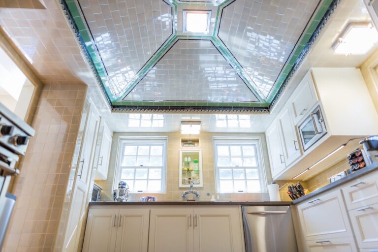 Modern kitchen with white cabinets, stainless steel appliances, and a unique tiled, skylit ceiling.