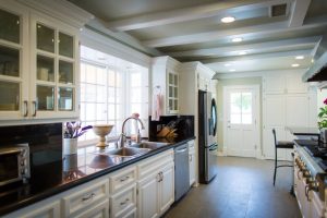 Bright, modern kitchen with white cabinets, stainless steel appliances, and large windows letting in natural light.