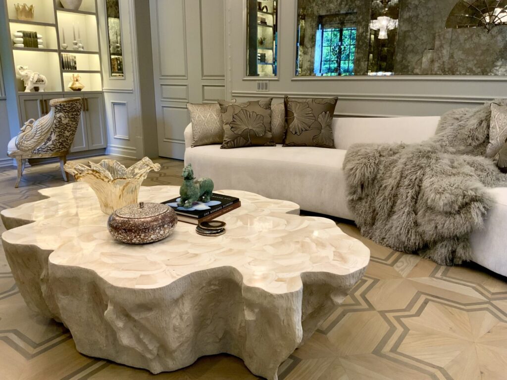 Elegant living room with a sculpted stone coffee table, white sofa, plush throw, and decorative accents.