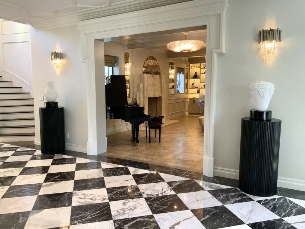 Spacious room with black grand piano, checkered marble floor, and elegant decor, including vases on pedestals.