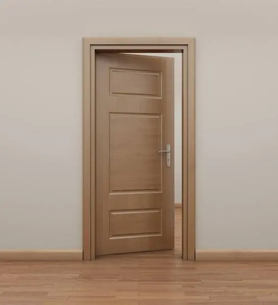 A light wooden door, slightly open, in a beige room with wooden flooring.