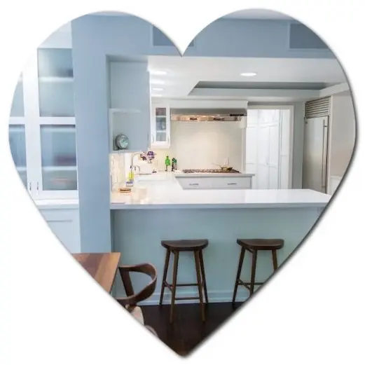 Heart-shaped frame around a modern Los Angeles kitchen with white counters, stools, and stainless steel appliances.