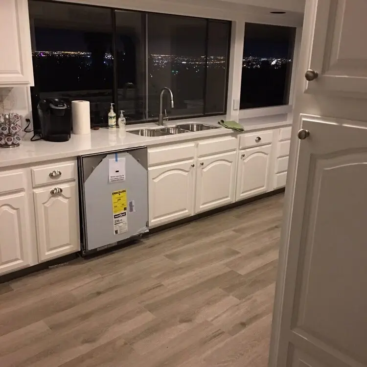 Modern kitchen with white cabinets and a dishwasher installed at an angle under the counter, facing outward.