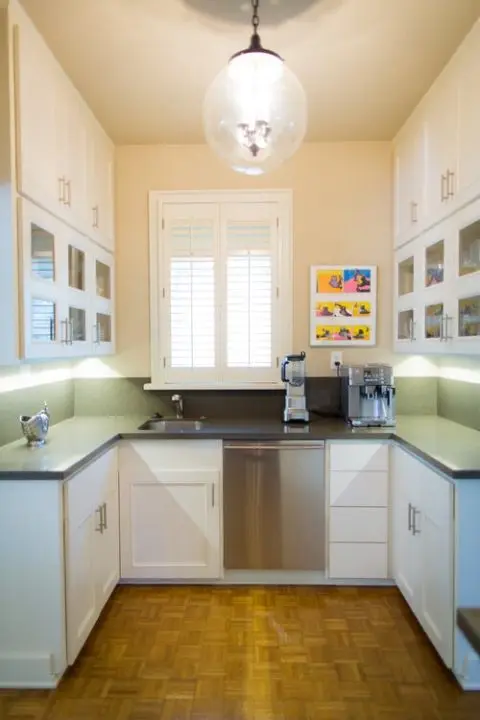 Bright galley kitchen with a cabinet refresh, white cabinets, stainless appliances, and a window with shutters above the sink.
