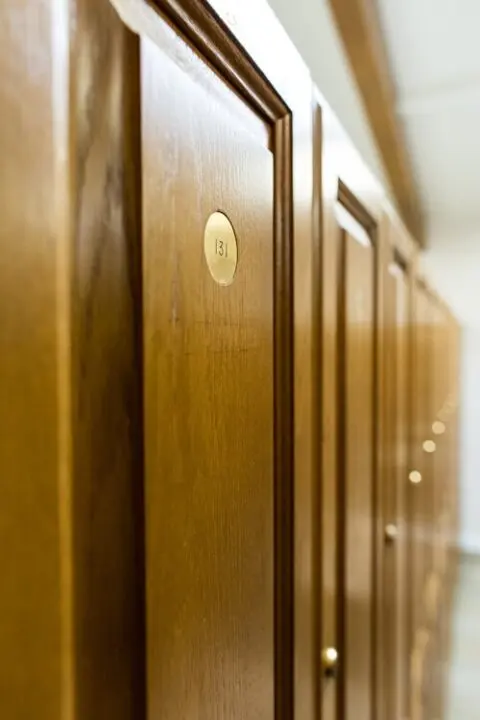 Close-up of wooden lockers with numbered brass plaques, focusing on locker number 13.