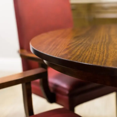 Close-up of a round wooden table with two red upholstered chairs in soft focus.