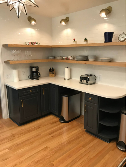 Modern kitchen with dark cabinets, open wooden shelves, appliances, dishes, and hardwood floors.