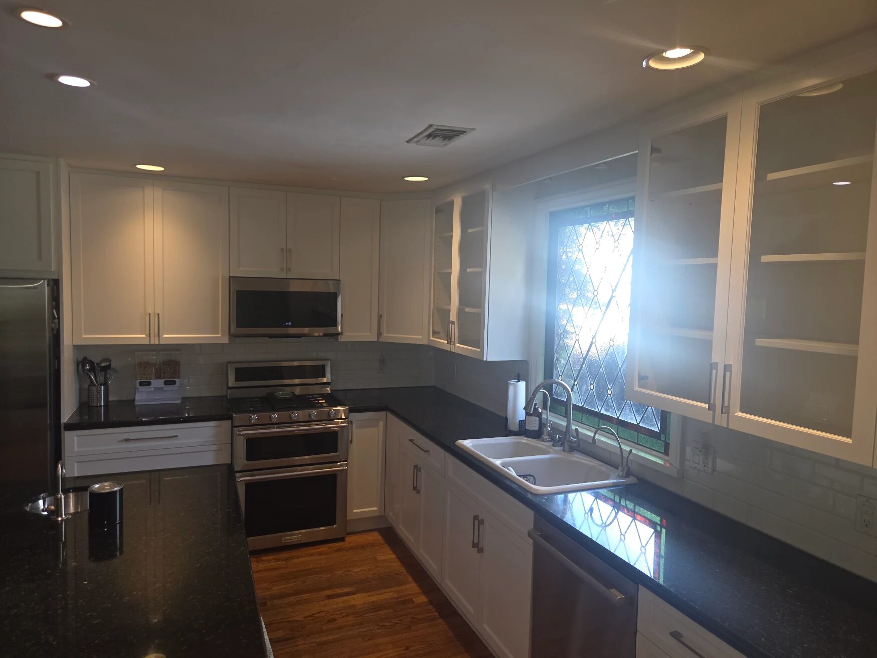 Modern White Kitchen with Black Granite Countertops and Stainless Steel Appliances